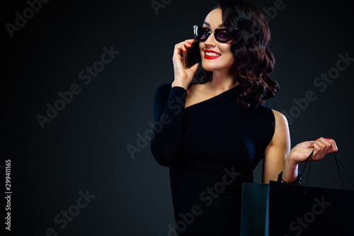 Shopping on Black Friday and Cyber Monday. Sale concept for shops. Woman holding bag and calling on the phone , isolated on dark background