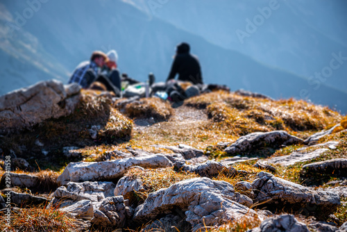 Autumn landscape in high mountains. In the background tourists resting on the top of the mountain after a tiring hike.