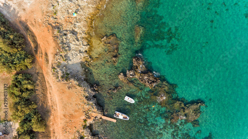 Aerial view of rocky beach on turquoise Adriatic Sea with boats moored near shore, Puglia coastline, southern region of Italy.