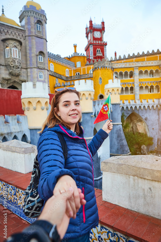 Young woman tourist walks in Pena Palace, Sintra holding the flag of Portugal in her hands. Travel and tourism in Europe