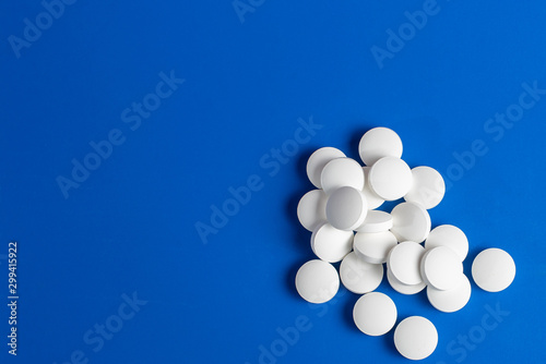white round pills scattered blue background  chaotically scattered.