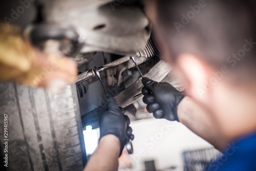 Auto mechanic repairer checking condition under car on vehicle lift