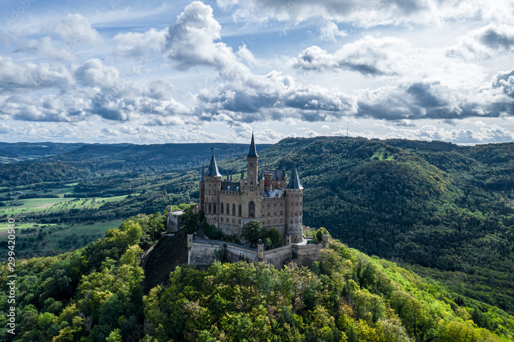 Aerial panorama of Burg Hohenzollern (Hohenzollern castle) with hills and villages surrounded by forests with beautiful foliage