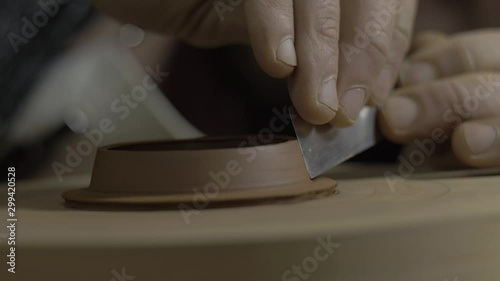 The master removes excess clay from the lid for the teapot from Yixing clay using a metal tool. Handmade clay teapot for tea ceremony. brown pottery teapot. 4k video. 59.94 fps