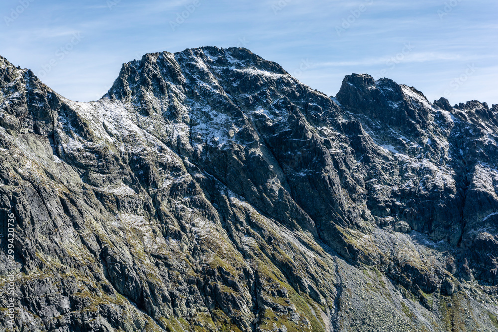 View of the mountain peaks and passes sprinkled with the first snow in the ridge in the autumn scenery. Tatra Mountains. Slovakia