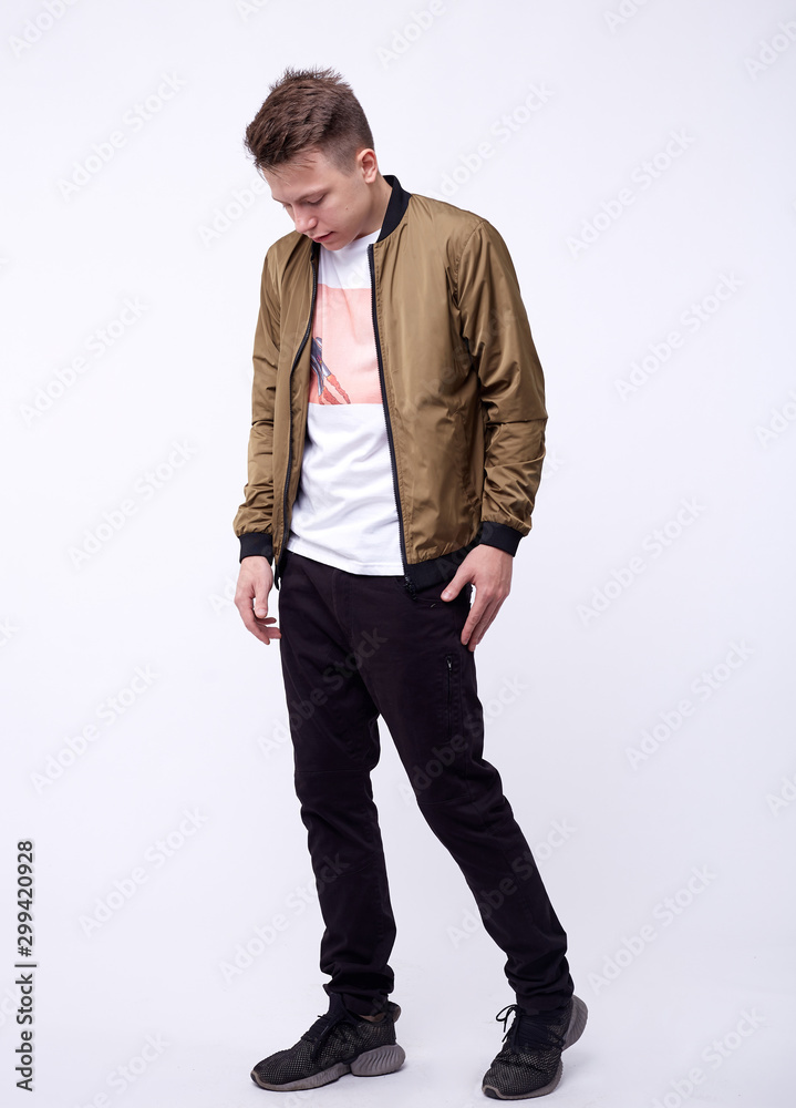 Young man in jeans, shiny nylon gold bomber jacket on white background. Young man in jeans, shiny nylon gold bomber jacket on white background.