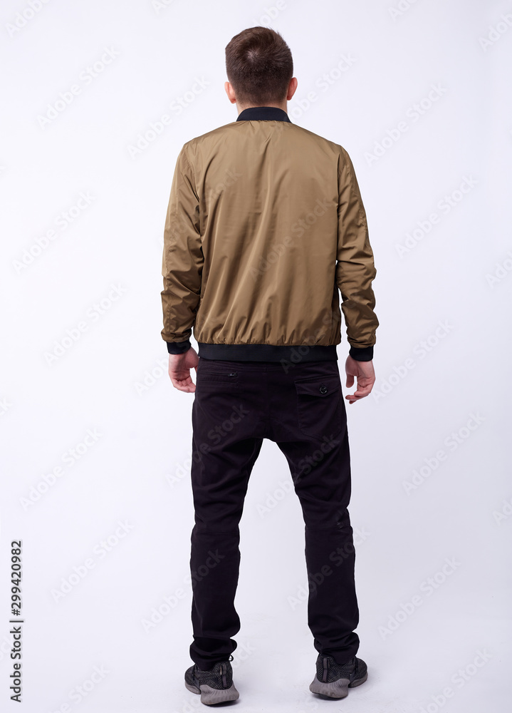Young man in jeans, shiny nylon gold bomber jacket on white background. Young man in jeans, shiny nylon gold bomber jacket on white background.