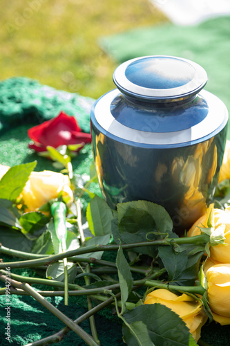Cremation urn with yellow roses, at an outdoor funeral