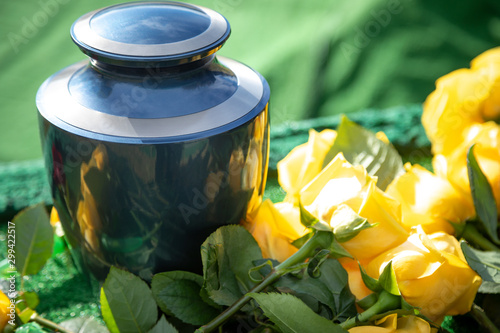 Urn with yellow roses, at an outdoor funeral with space for text photo