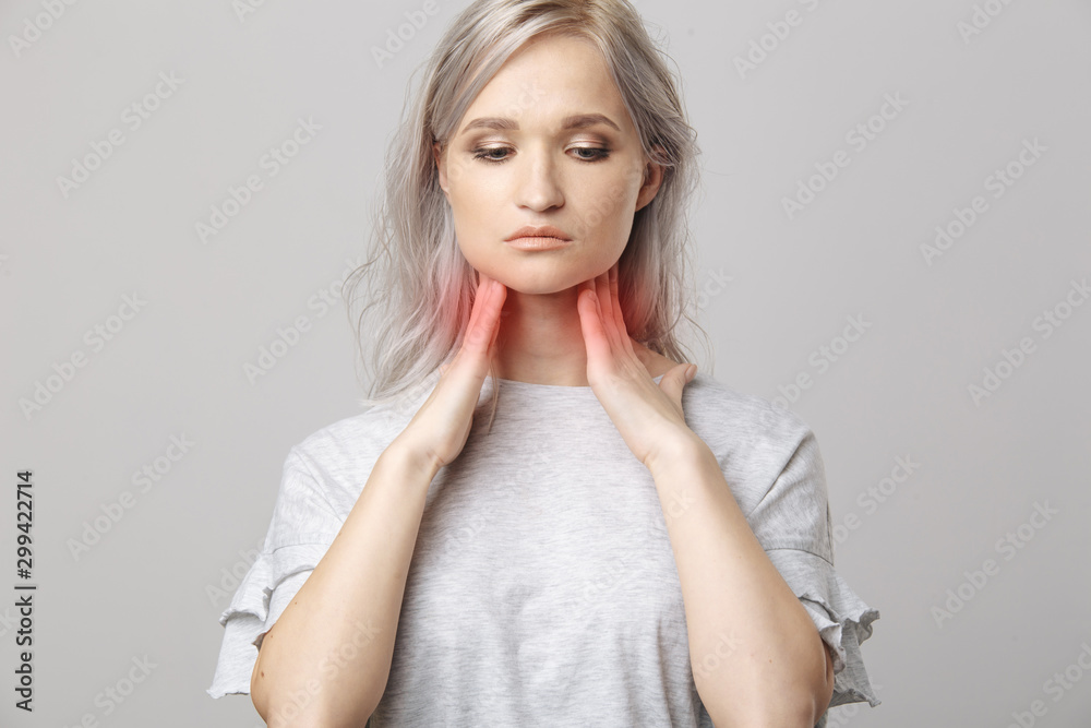 Female checking thyroid gland by herself. Close up of woman in white t- shirt touching neck with red spot. Thyroid disorder includes goiter, hyperthyroid, hypothyroid, tumor or cancer Health care. Female checking thyroid gland by herself. Close up of woman in white t- shirt touching neck with red spot. Thyroid disorder includes goiter, hyperthyroid, hypothyroid, tumor or cancer Health care.