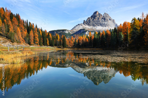 Lake with reflection of mountains at sunset in autumn, Dolomites, Italy. Landscape with Antorno lake, trees with orange leaves and high rocks in fall. Colorful forest