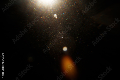 Lens Flare. Light over black background. Easy to add overlay or screen filter over photos. Abstract sun burst with digital lens flare background. Gleams rounded and hexagonal shapes, rainbow halo.