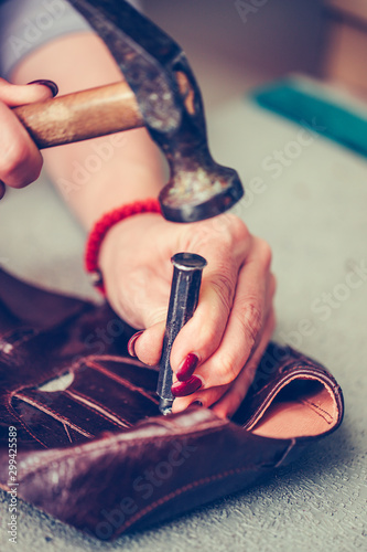 Female shoemaker working with leather using crafting tools