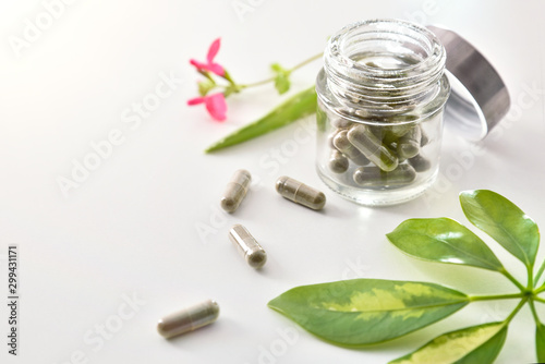 Natural medicine capsules in open glass jar on table elevated