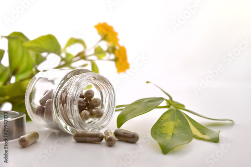 Natural medicine capsules in open glass jar on table front