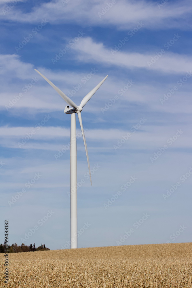 View of a giant wind power generator on an autumn agricultural field landscape with a blue sky background View of a giant wind power generator on an autumn agricultural field landscape with a blue sky background