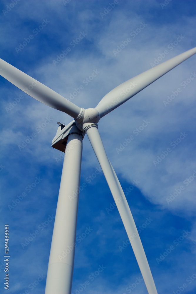 Close upward view of a giant wind power turbine propeller with a blue sky background Close upward view of a giant wind power turbine propeller with a blue sky background