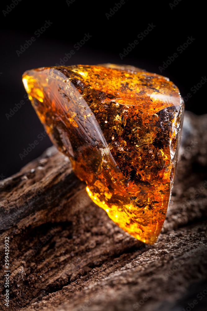 Natural amber stone. A piece of dirty transparent yellow amber on piece of stoned wood. Natural amber stone. A piece of dirty transparent yellow amber on piece of stoned wood.