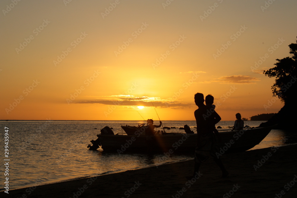 silhouette of people on the beach at sunset with boat