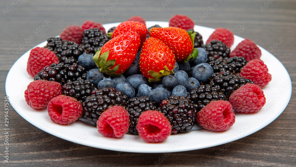 Blackberry, raspberry blueberry and strawberry on a white plate. Vitamins and wholesome foods