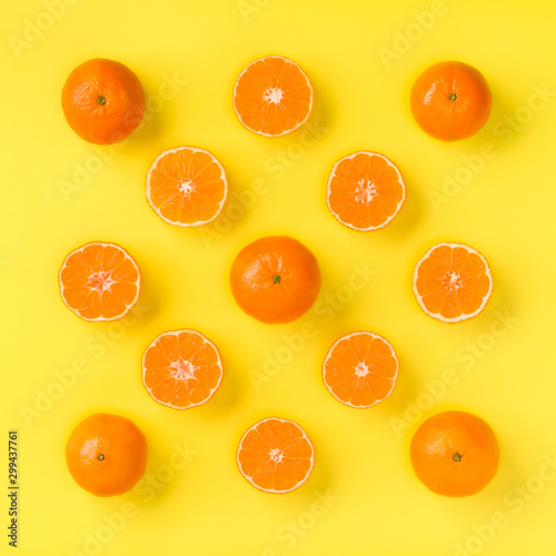 Fruit pattern of fresh mandarin slices on yellow background. Flat lay, top view. Pop art design, creative summer concept. Half of citrus in minimal style. Tangerine.