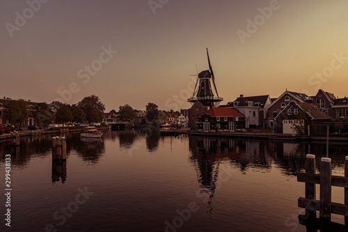 Boat anchored on a canal in Amsterdam at sunrise, windmill