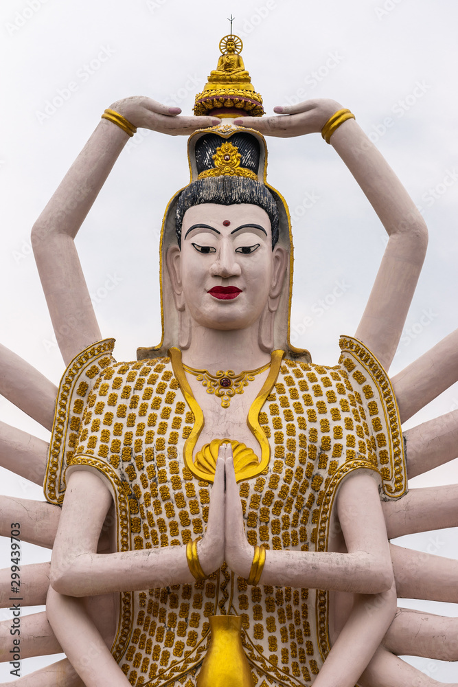Obraz premium Ko Samui Island, Thailand - March 18, 2019: Wat Laem Suwannaram Chinese Buddhist Temple. Closeup of chest and heast of Giant Guan Yin goddess statue with 18 arms against silver sky.