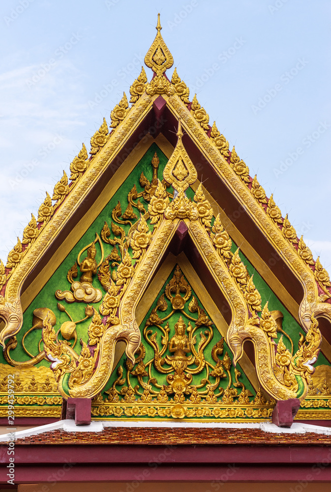 Fototapeta premium Ko Samui Island, Thailand - March 18, 2019: Wat Laem Suwannaram Chinese Buddhist Temple. Golden gable with Guan Yin statue against light blue sky.