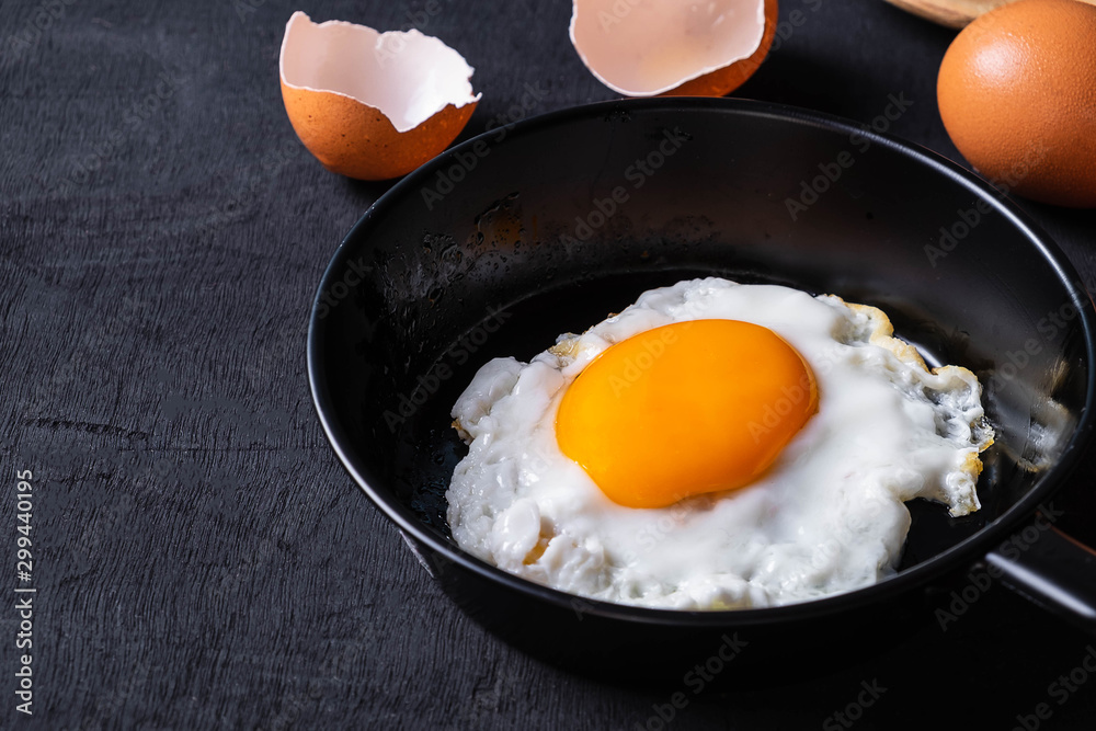 Fried eggs in a frying pan and egg shell for breakfast on a black background. Fried eggs in a frying pan and egg shell for breakfast on a black background.