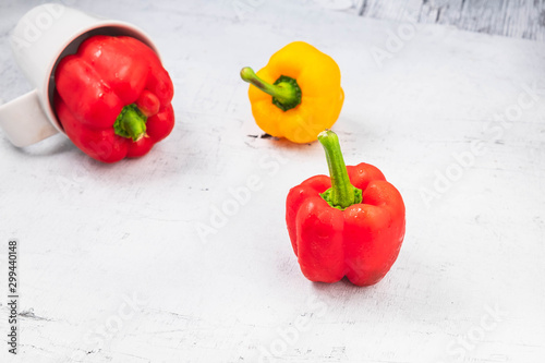 Fresh red and yellow bell peppers on a white wooden background.