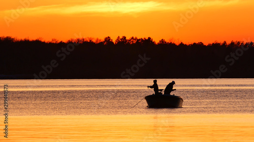 Obraz na płótnie Silhouette of father and son fishing on a beautiful lake at sunset in northern Minnesota. w salonie