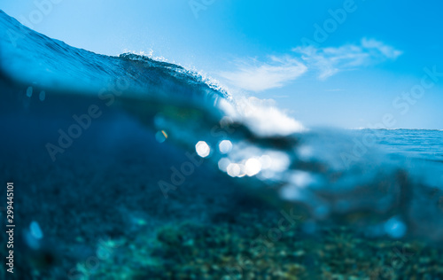 Ocean wave breaks in the ocean over the coral reef. Splitted  above - under view