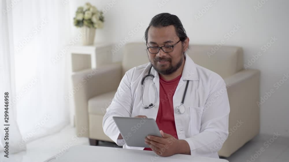 portrait of busy doctor using tablet pc in his office and smiling portrait of busy doctor using tablet pc in his office and smiling