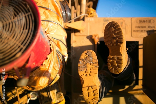 Rope access miner wearing safety boot harness, helmet entering into confined space manhole door construction mine site Perth, Australia 