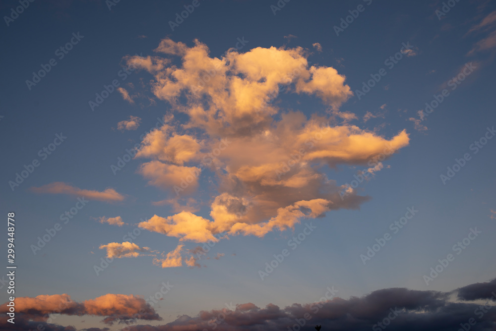 Dramatic clouds lit by setting sunset against dark blue sky Dramatic clouds lit by setting sunset against dark blue sky