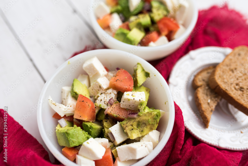 healthy salad from fresh vegetables with avocado, tomatoes and fresh mozzarella cheese served in white bowl healthy salad from fresh vegetables with avocado, tomatoes and fresh mozzarella cheese served in white bowl