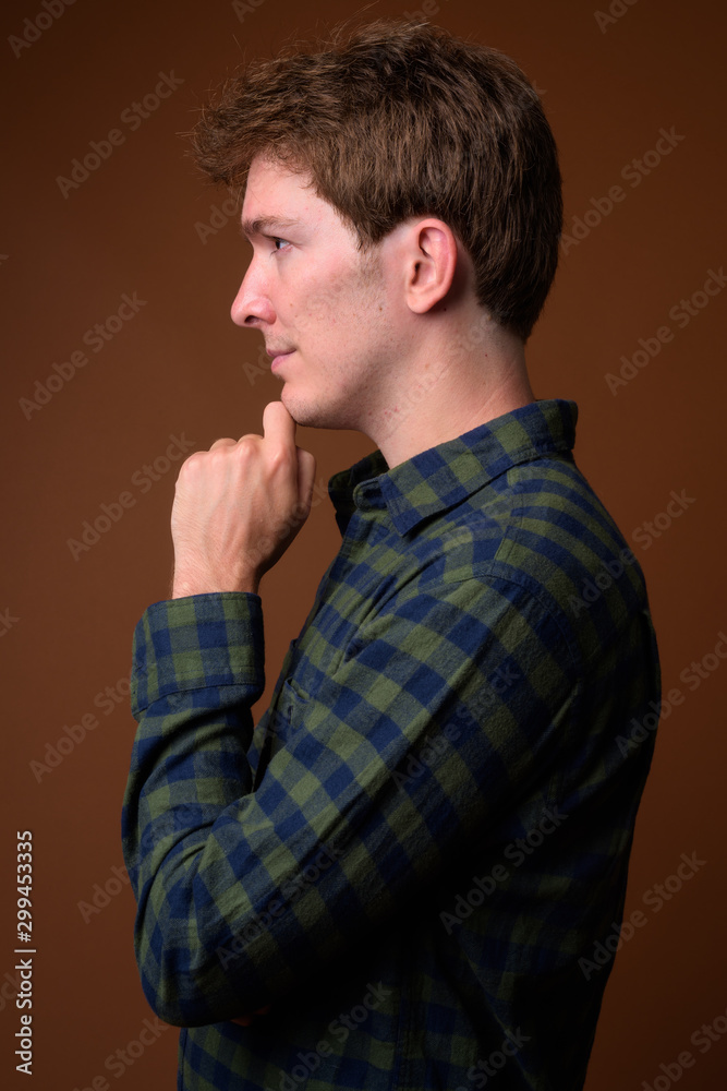 Profile view of young handsome hipster man in green checkered shirt Profile view of young handsome hipster man in green checkered shirt