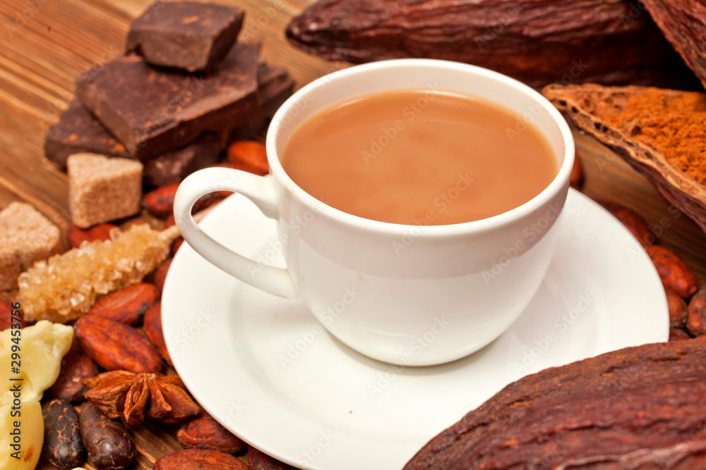 Cup of cacao drink with cocoa pods, cacao powder, cocoa butter, chocolate, sugar, cacao beans and star anise on a wooden background. Cup of cacao drink with cocoa pods, cacao powder, cocoa butter, chocolate, sugar, cacao beans and star anise on a wooden background.