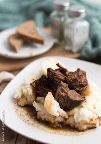 Beef tips with gravy on mashed potatoes served on white plate