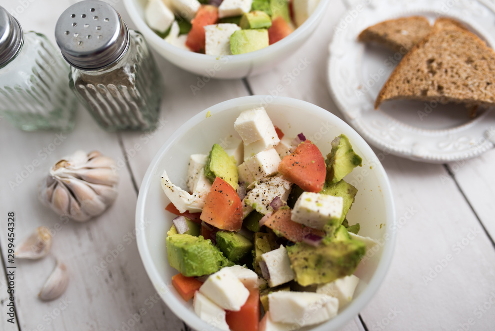 healthy salad from fresh vegetables with avocado, tomatoes and fresh mozzarella cheese served in white bowl healthy salad from fresh vegetables with avocado, tomatoes and fresh mozzarella cheese served in white bowl