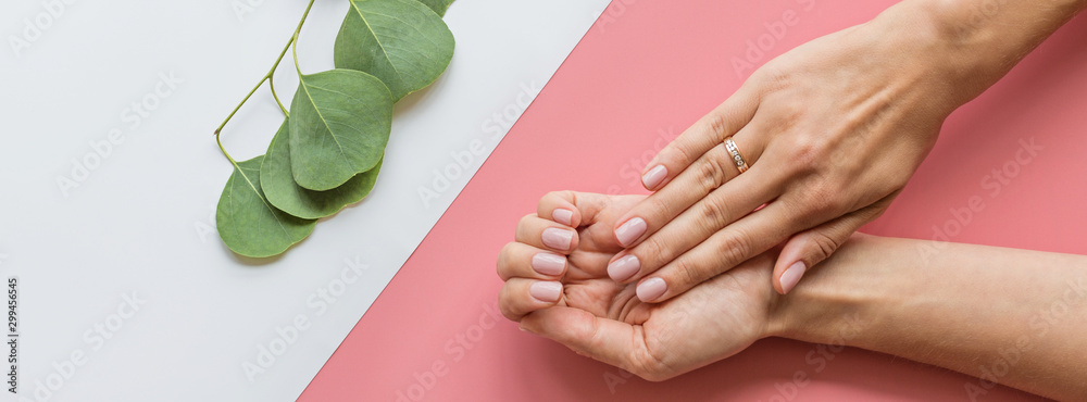 Stylish trendy female pink manicure. Beautiful young woman hands on pink pastel background with flowers and place for text. Minimal creative concept. Flat lay, top view, mock up, copy space, template - obrazy, fototapety, plakaty 