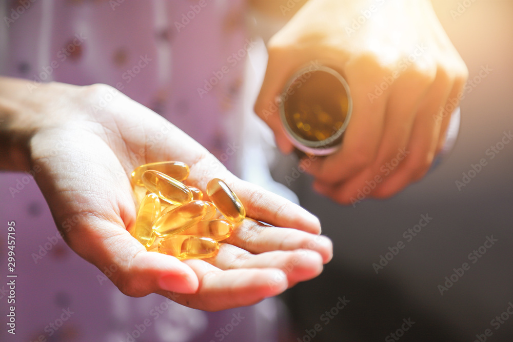 Hand pouring fish oil from bottle for health care eating in daily life Hand pouring fish oil from bottle for health care eating in daily life