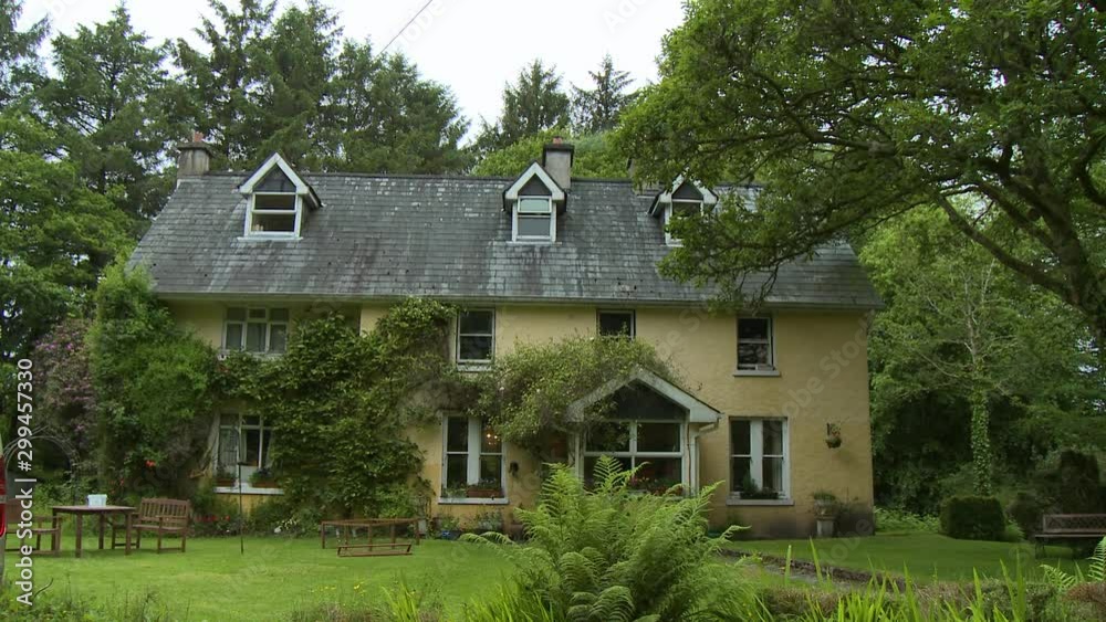 Wide view of the front of a yellow three story house with a picnic table out front, several large windows, and ivy growing on the walls Wide view of the front of a yellow three story house with a picnic table out front, several large windows, and ivy growing on the walls