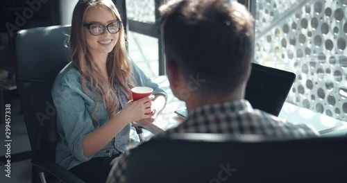 Man and woman office employees having coffee break, relaxing during working day and chatting, attractive lady smiling