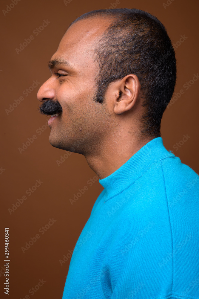 Obraz premium Closeup profile view of happy Indian man with mustache wearing blue sweater