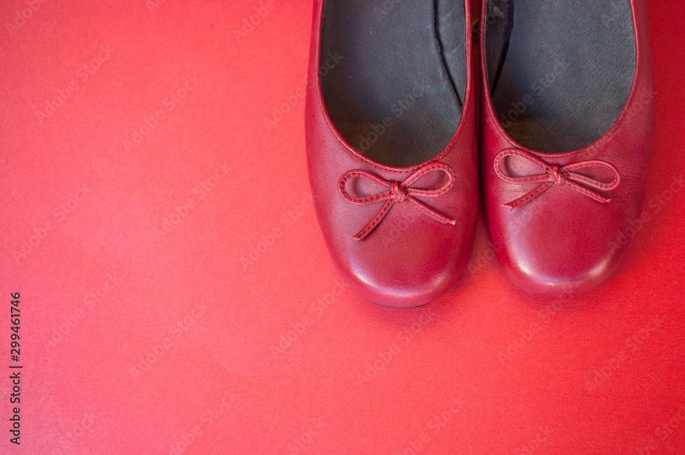 Stylish female flat shoes in dark red color on dark red background with copyspace. Beauty and fashion concept. Stylish female flat shoes in dark red color on dark red background with copyspace. Beauty and fashion concept.