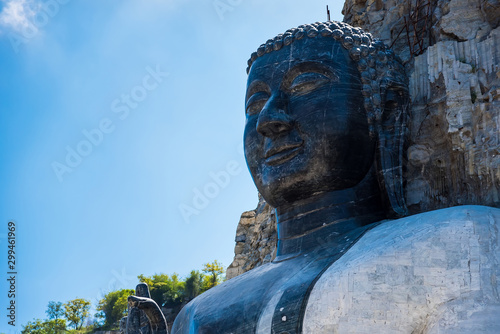 Suphan Buri, Thailand - October 27, 2019: Rock Buddha Statue at Wat Khao Tham Thiam, Rock Buddha statue carved from cliffs of the rocky mountain at Suphan Buri, Thailand photo