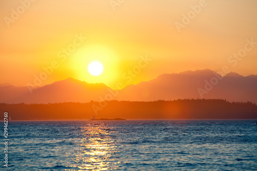 Orange sunset behind mountains with lake in foreground