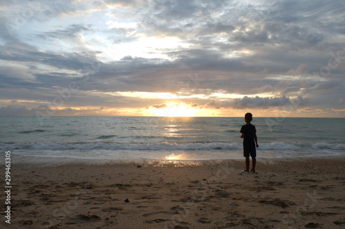 young man walking on the beach at sunset