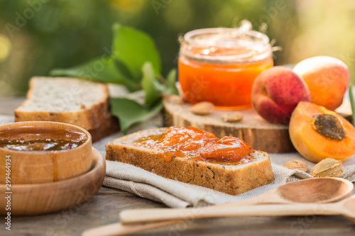 Apricot jam and ripe apricots on the wooden natural table.